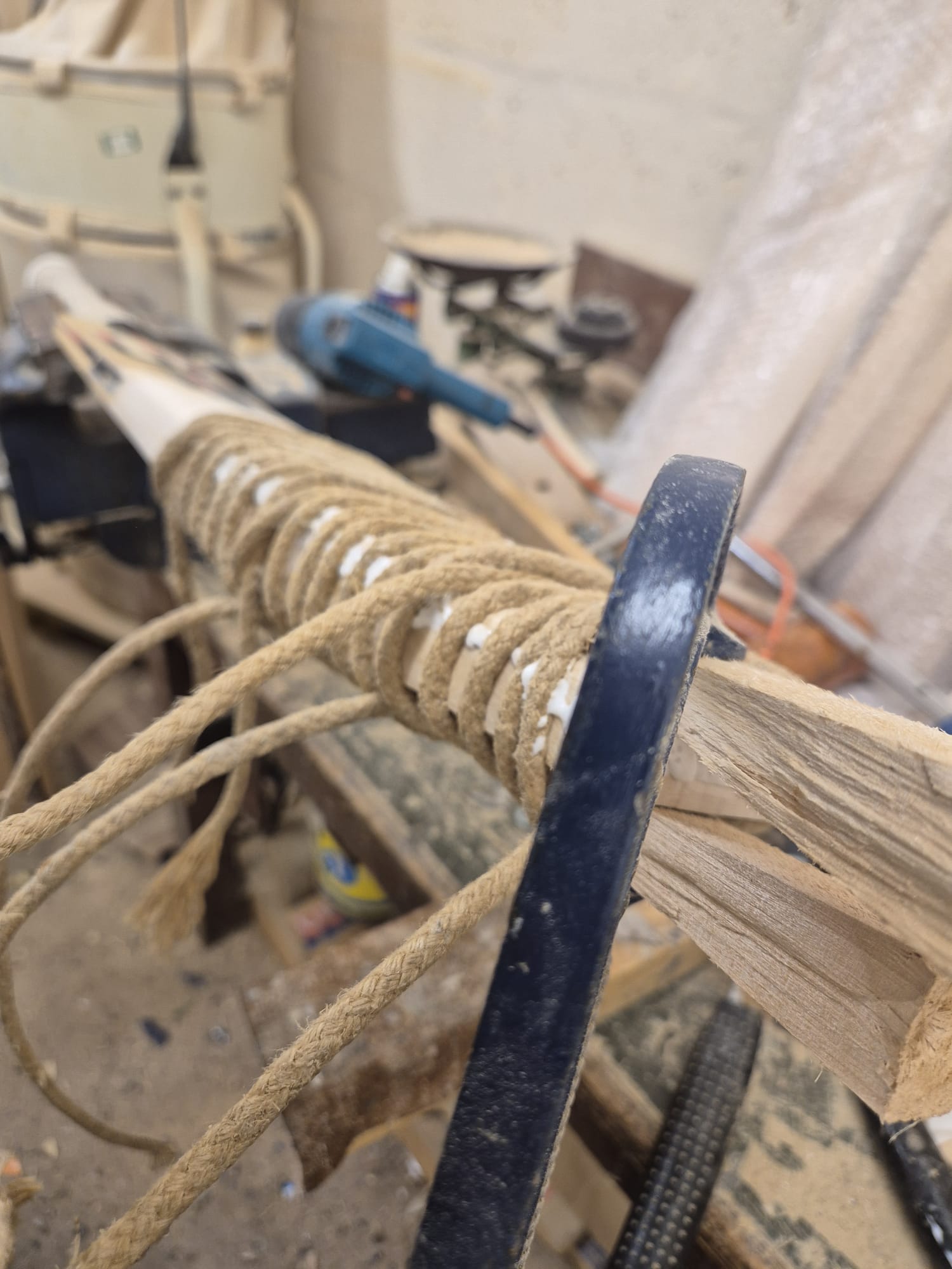 Close-up of a cricket bat being expertly restored at Martin Berrill Sports during their Pre Season & End of Season Clean up, with tools and workbench visible—showcasing craftsmanship akin to sword handle wrapping.