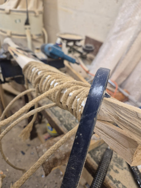 Close-up of a cricket bat being expertly restored at Martin Berrill Sports during their Pre Season & End of Season Clean up, with tools and workbench visible—showcasing craftsmanship akin to sword handle wrapping.