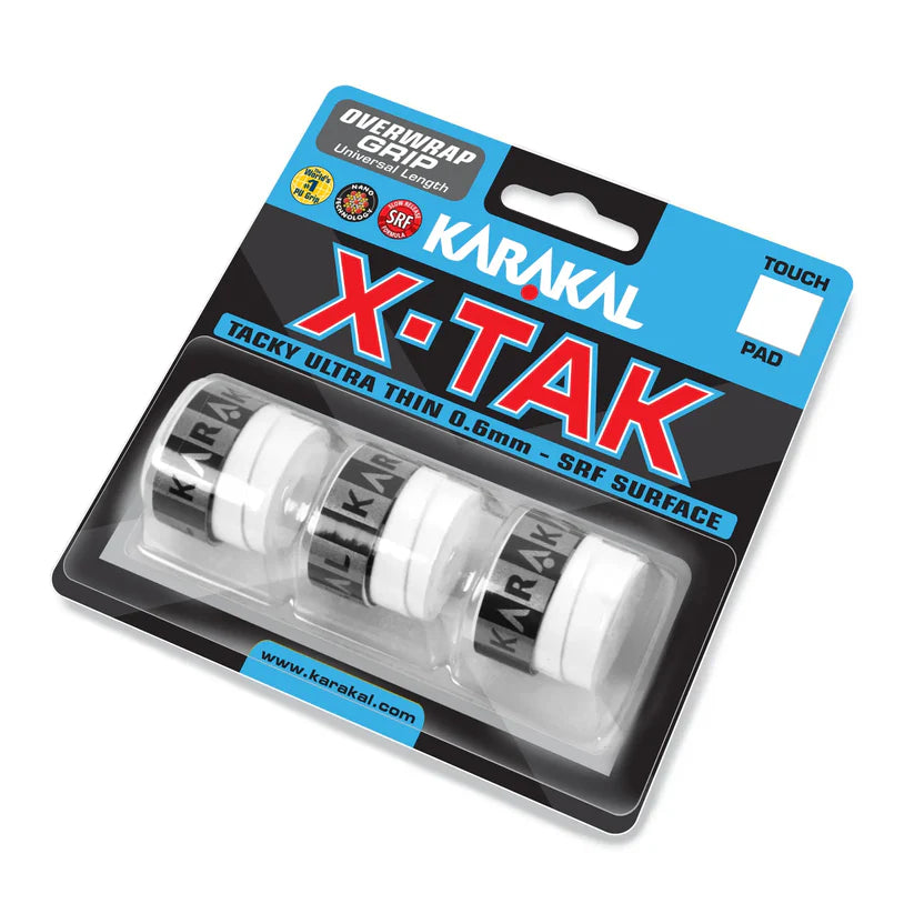 A retail pack of Karakal X-TAK Overwrap Grip features three white, ultra-thin, tacky grips with black Karakal branding, displayed in clear plastic on a black and blue cardboard backing.