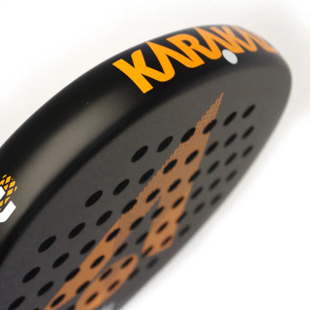 Close-up of the Karakal Air Lite 345 Padel - Orange by Karakal, featuring a lightweight graphite frame with bold orange branding and a striking pattern of dots and lines on its black face.