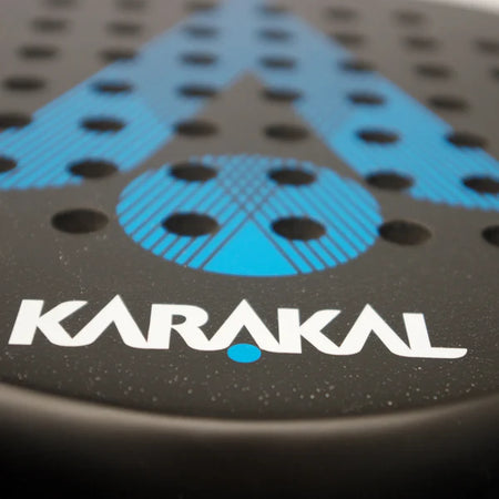 Close-up of the Karakal Air Lite 345 Padel - Blue by Karakal, showing its lightweight graphite build, black frame with blue accents, multiple holes, and bold white KARAKAL branding near the bottom.