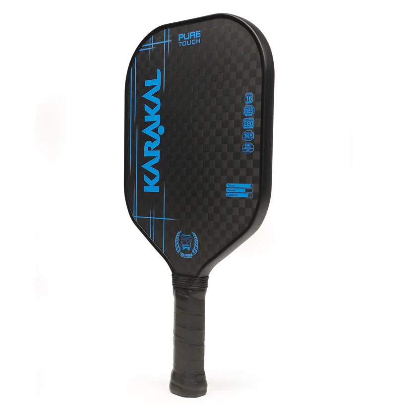 The Karakal Pure Touch Blue Pickleball Paddle features a black and blue checkered, textured face with specifications, a honeycomb power core, PURE TOUCH branding, and a wrapped grip handle.