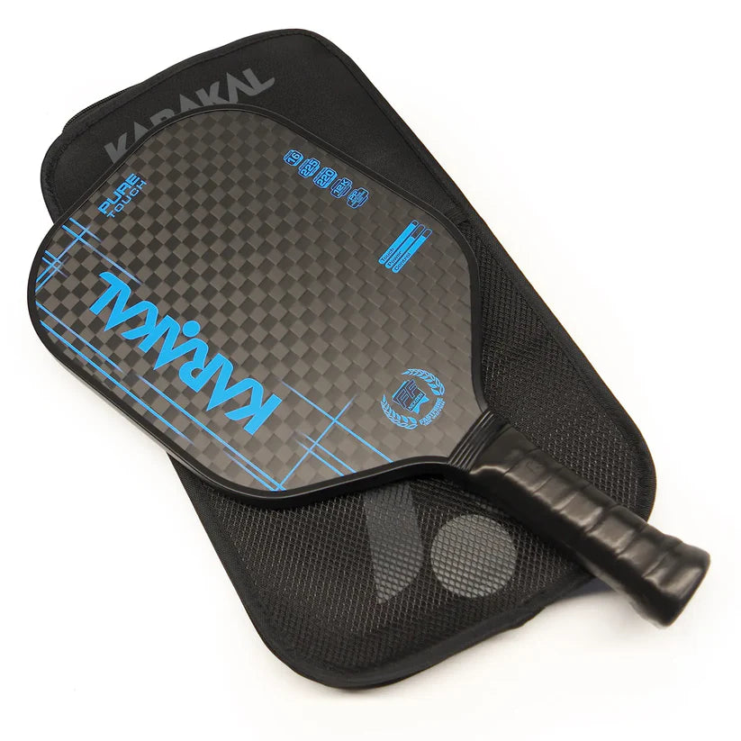 The Karakal Pure Touch Blue Pickleball Paddle by Karakal features a black paddle with blue accents, a textured surface, honeycomb power core for performance, and a comfortable black grip. It rests on a matching black zippered carrying case.