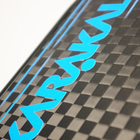 Close-up of the Karakal Pure Touch Blue Pickleball Paddle’s carbon fiber surface with a checkered texture, blue KARAKAL logo, thin blue lines, and a honeycomb power core.