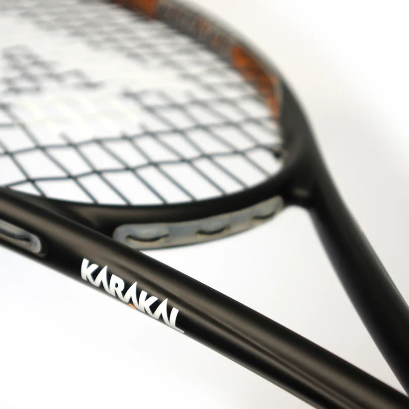 Close-up of the Karakal Air Touch 2.1 Squash Racket by Karakal, made from high modulus graphite, featuring the brand name on its frame with strings visible in the background.