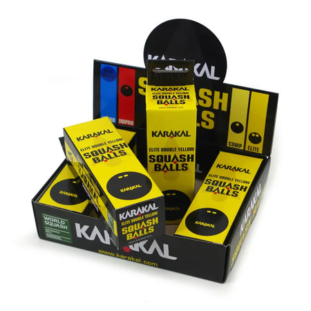A display box with several Karakal Double Yellow Dot Squash Balls packages, each showing the Karakal branding and labels on WSF approved, tournament-grade squash balls.