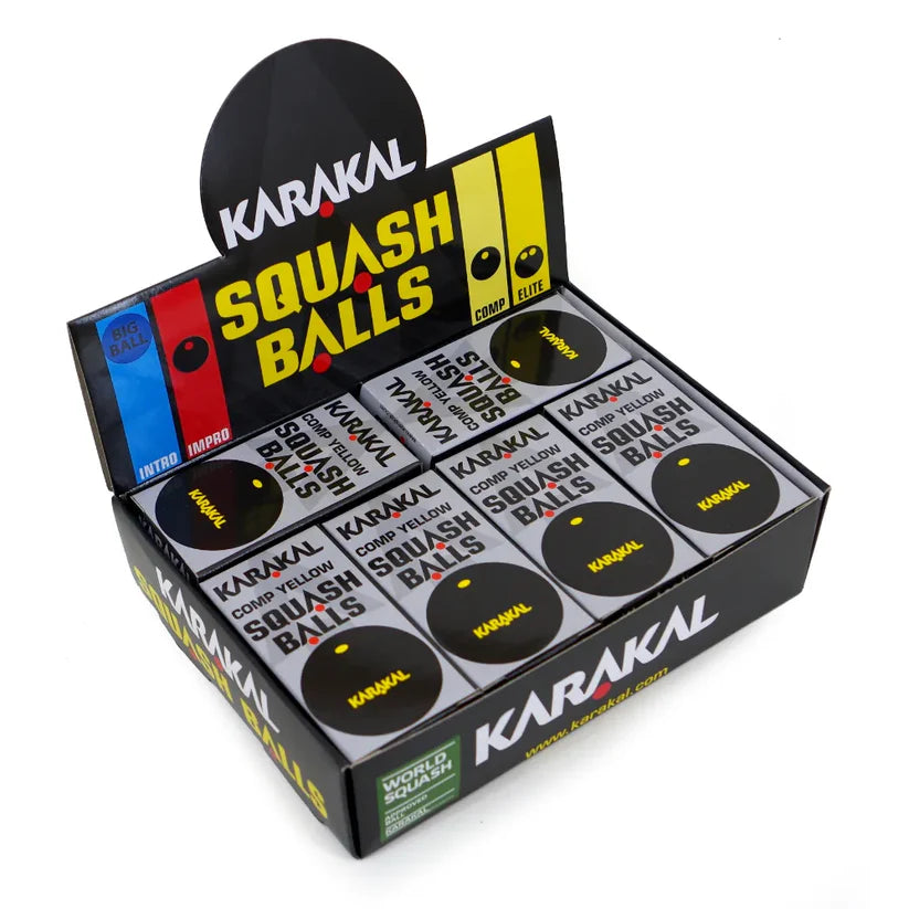 A display box of Karakal Yellow Dot Squash Balls by Karakal, containing several tubes of black, WSF-approved club-level balls. The mainly black packaging features yellow, red, and blue accents with bold "Squash Balls" labeling.