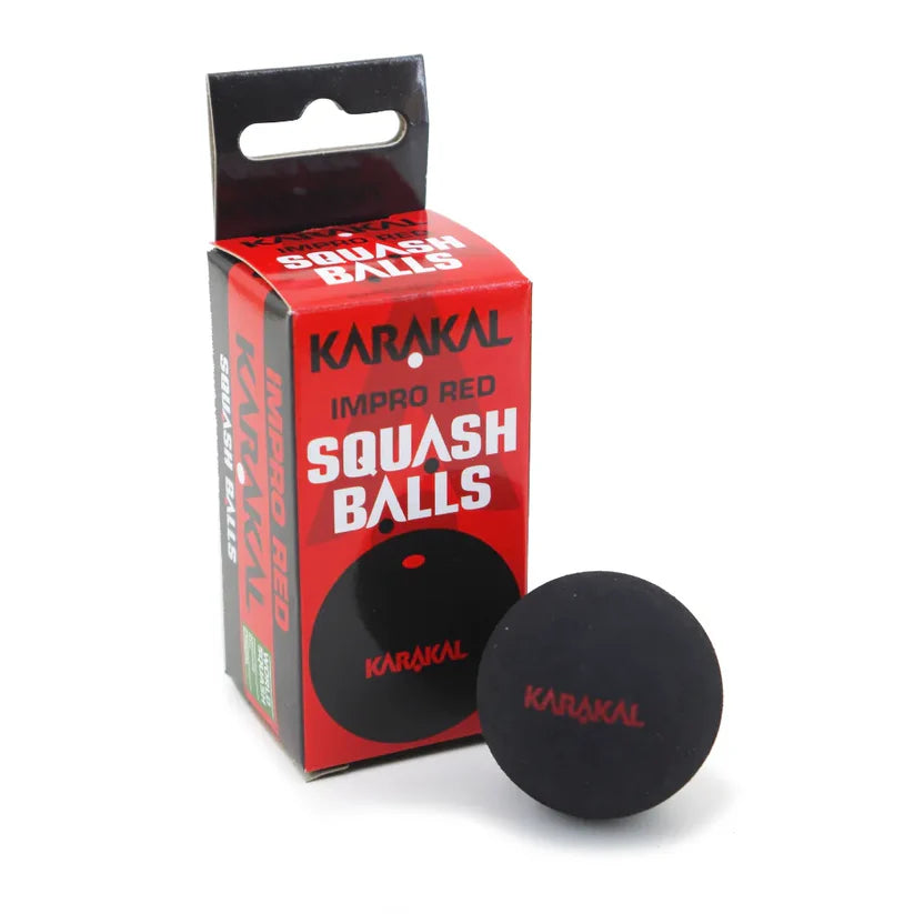 A black Karakal Red Dot Squash Ball, suitable for intermediate players, sits before its red and black Karakal Red Dot Squash Balls packaging.