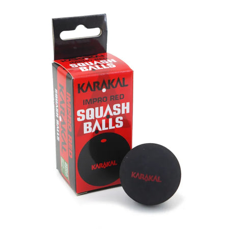 A black Karakal Red Dot Squash Ball, suitable for intermediate players, sits before its red and black Karakal Red Dot Squash Balls packaging.