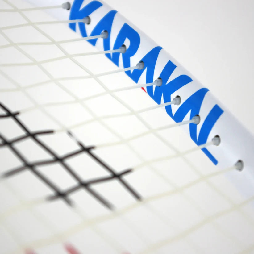 Close-up of the Karakal CRX-Tour 2.1 Racketball Racket, featuring blue Karakal branding on the midplus head and white strings with a black pattern, highlighting its durable 7050 alloy against a plain, light-colored background.