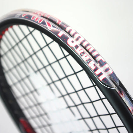 Close-up of a Karakal Air Power 2.1 Squash Racket in black and red on a white background, highlighting the strings, part of the high modulus graphite frame, and visible Karakal branding.
