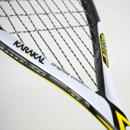 Close-up of the ultra-light Karakal Raw 120 2.1 Squash Racket, showing its strings and part of the white, black, and yellow frame with Karakal branding and graphics collection text visible.