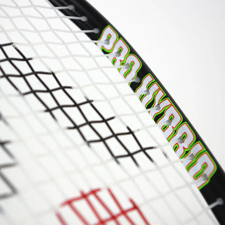 Close-up of the Karakal Pro Hybrid 2.1 Squash Racket by Karakal, displaying "PRO HYBRID" on its black frame with white strings and a partial red logo in the background. This racket is known for its lightweight, advanced design.