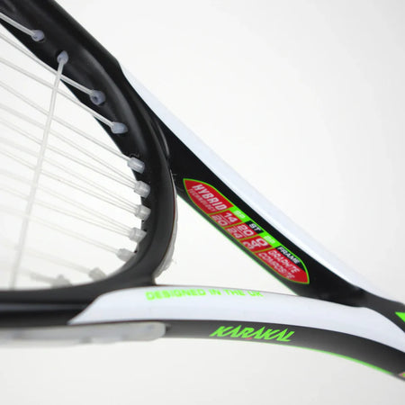 Close-up of a Karakal Pro Hybrid 2.1 Squash Racket in black, white, and green, featuring visible strings, the KARAKAL logo, and “DESIGNED IN THE UK” stickers that showcase this lightweight racket’s premium quality.