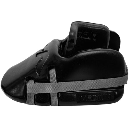 The Mercian Genesis 2 Kickers, high-density foam sparring foot guards in black with a gray elastic strap and “MEDIUM” size label, feature a custom-fit design. Shown from the side on a white background.