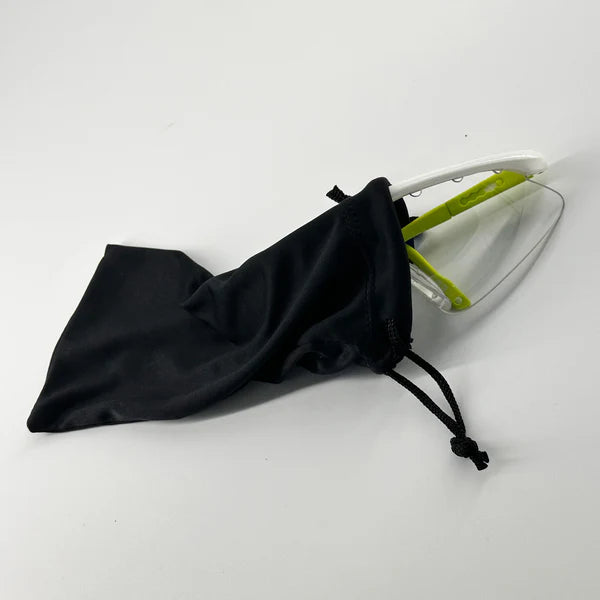 A pair of Karakal Pro 2500 Sports Eye Protection goggles for ladies/juniors, in green and white, partially tucked into a black Karakal pouch, resting on a white surface.