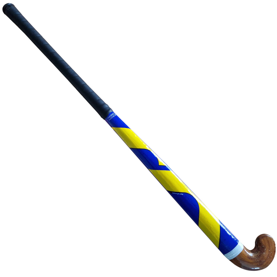 The Mercian Maestro Hockey Stick by Mercian is perfect for beginners, with a black cotton tape grip, curved wooden end, and a shaft featuring a bold yellow and blue zigzag design.