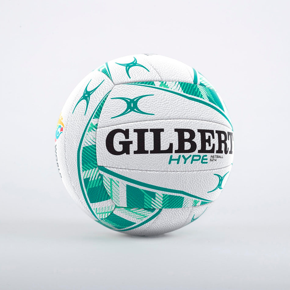 The Gilbert Hype Match Netball by Gilbert is a white Size 5 netball with green and teal geometric patterns, bold black branding, and a premium match-quality design, displayed on a plain light gray background.