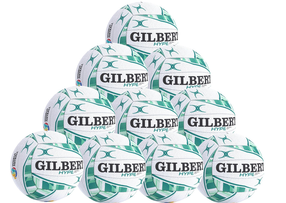 A pyramid stack of ten white and green Gilbert Hype Match Netballs—a high-quality rubber ball for match and training, each featuring GILBERT and HYPE branding. Product: Gilbert Hype Match Netball Ten Pack by Gilbert.