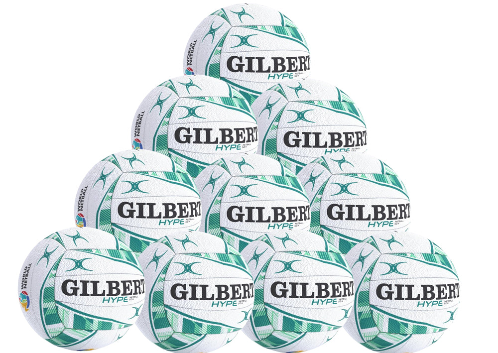 A pyramid stack of ten white and green Gilbert Hype Match Netballs—a high-quality rubber ball for match and training, each featuring GILBERT and HYPE branding. Product: Gilbert Hype Match Netball Ten Pack by Gilbert.