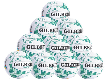 A pyramid stack of ten white and green Gilbert Hype Match Netballs—a high-quality rubber ball for match and training, each featuring GILBERT and HYPE branding. Product: Gilbert Hype Match Netball Ten Pack by Gilbert.