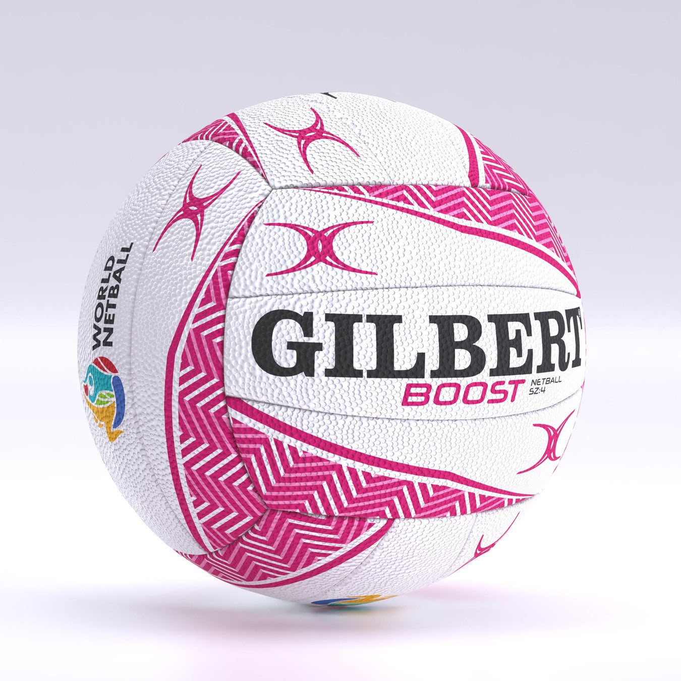 The Gilbert Boost Match Netball is a white size 5 ball featuring pink geometric patterns, bold black GILBERT branding, BOOST in pink, and a colorful World Netball logo. It has a design similar to Gilbert match balls and rugby balls.