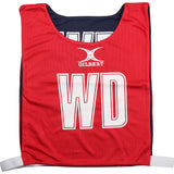 The Gilbert Reversible Netball Bibs in red/navy feature the GILBERT logo and large white WD letters on the front, with white hook-and-loop side straps for easy fitting—perfect for any netball bib collection.