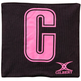 The Gilbert Pro Patch Bibs by Gilbert feature a black design with a large pink center "C" and the pink GILBERT logo at the bottom right—perfect for team player identification during netball training.