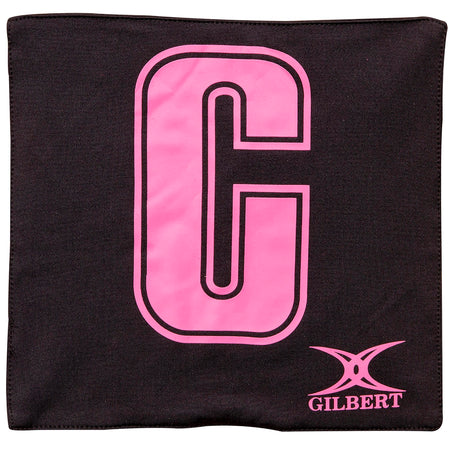 The Gilbert Pro Patch Bibs by Gilbert feature a black design with a large pink center "C" and the pink GILBERT logo at the bottom right—perfect for team player identification during netball training.