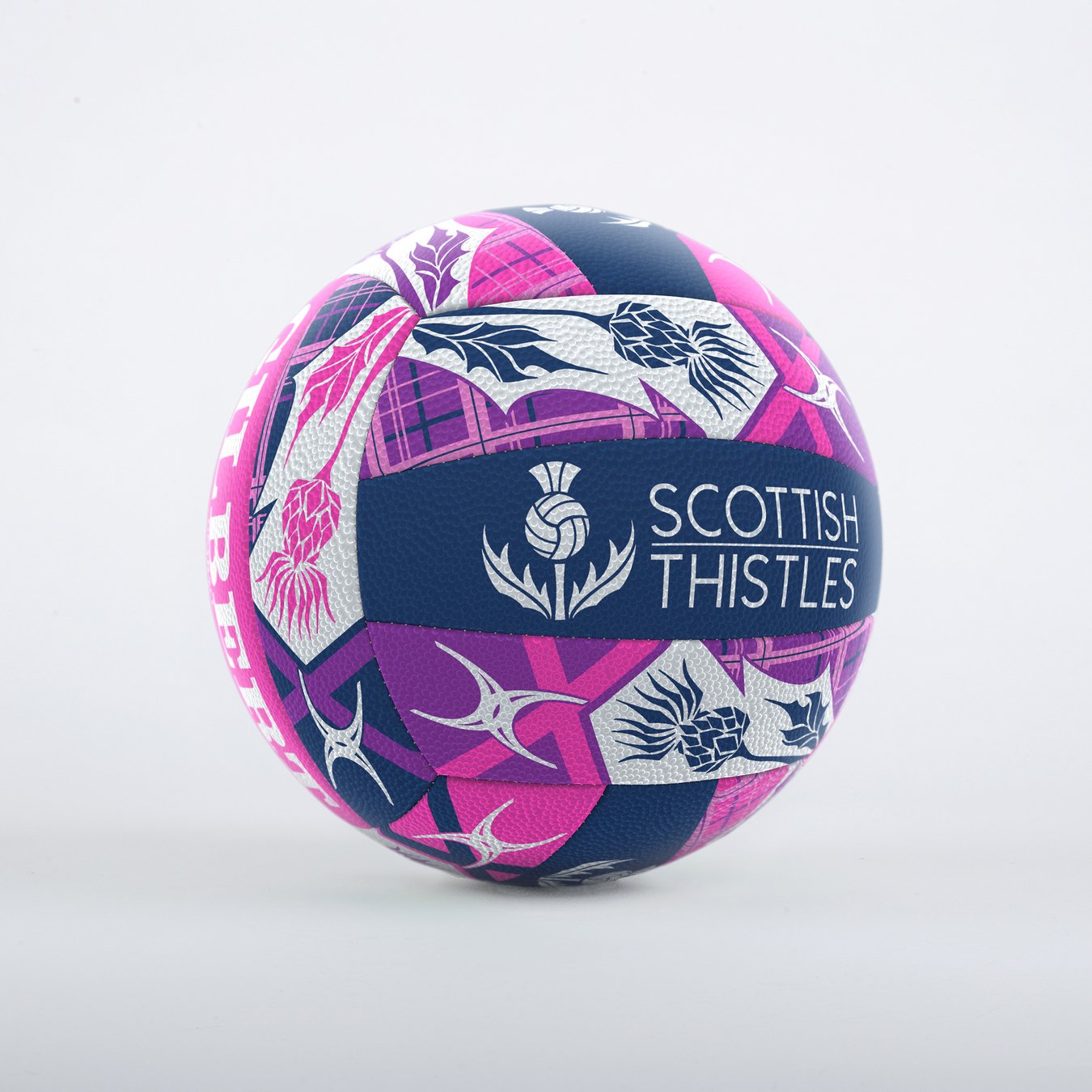 The Gilbert Scotland Supporter Netball is a colorful Size 5 ball with blue, pink, and white geometric and floral designs, “Scottish Thistles” text, a thistle logo, and Duragrip for control—perfect for Scotland fans.