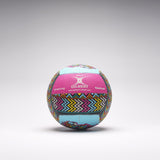 A vibrant Gilbert Ambassador Signature Netball in size 5, featuring zigzag and geometric pink, blue, yellow, and black patterns, rests on a light gray surface. Both "Gilbert" and "Training" are visible on this signature ball.