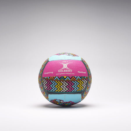 A vibrant Gilbert Ambassador Signature Netball in size 5, featuring zigzag and geometric pink, blue, yellow, and black patterns, rests on a light gray surface. Both "Gilbert" and "Training" are visible on this signature ball.