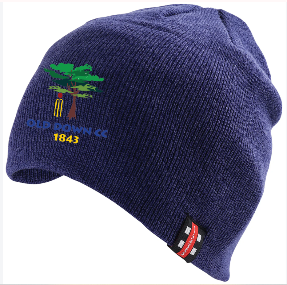 The Old Down CC Beanie Hat by Gray Nicolls is dark navy with an embroidered club logo showing a tree, cricket stumps, "OLD DOWN CC," "1843," and a small red and black Beechfield Original Headwear tag.
