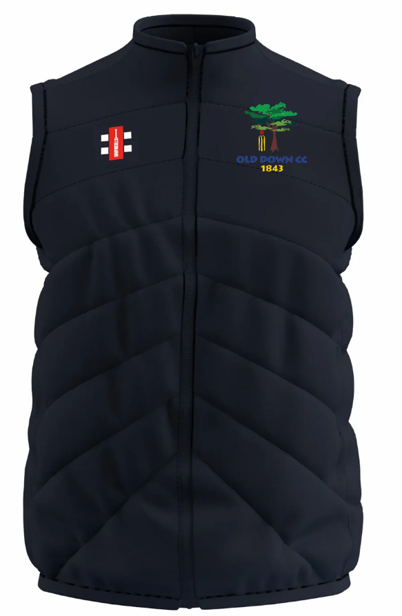 The Old Down CC GTS Body Warmer by Gray Nicolls is a sleeveless navy padded vest with a red and white rectangular logo on the left chest and an embroidered green tree with “OLD DOWN CC 1843” on the right chest.