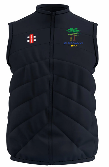 The Old Down CC GTS Body Warmer by Gray Nicolls is a sleeveless navy padded vest with a red and white rectangular logo on the left chest and an embroidered green tree with “OLD DOWN CC 1843” on the right chest.