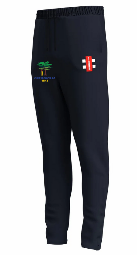 The Gray Nicolls Old Down CC GTS Men's Training Trousers are navy blue, slim fit with an elasticated waist, embroidered tree emblem and "Old Down CC 1843" on the left thigh, plus a red-white-black logo on the right.