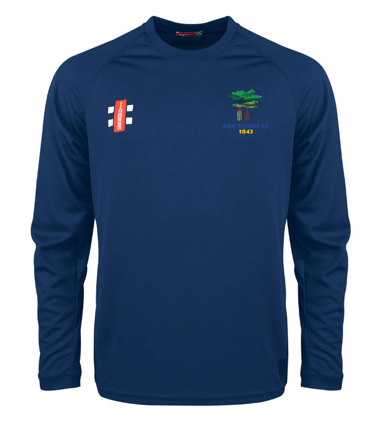 The Gray Nicolls Old Down CC Matrix V2 L/S Training Shirt is a navy, long sleeve, moisture-wicking crew neck with a small red logo on the right chest and an embroidered tree emblem with OLD DOWN CC 1843 on the left. No collar for comfort.