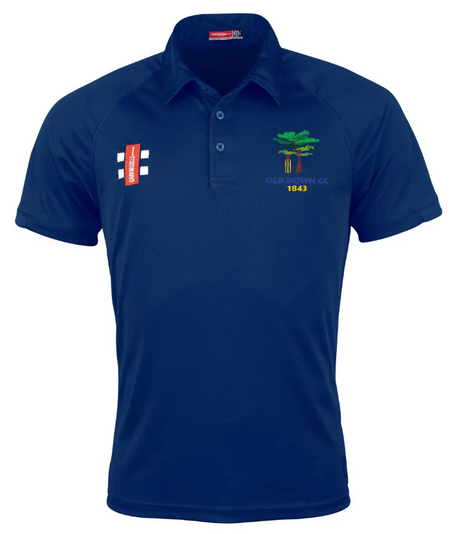 The Gray Nicolls Old Down CC Matrix V2 Polo is a navy short-sleeve, collared shirt with red and white chest patches and a tree logo with "OLD DOWN CC 1843" on the left. Designed for comfort and moisture management.