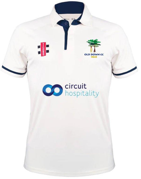 The Gray Nicolls Old Down CC Pro Performance V3 S/S Cricket Shirt features a white design with navy trim, anti-UV fabric, Old Down CC 1845 and sponsor logos, plus a navy collar with a button placket.