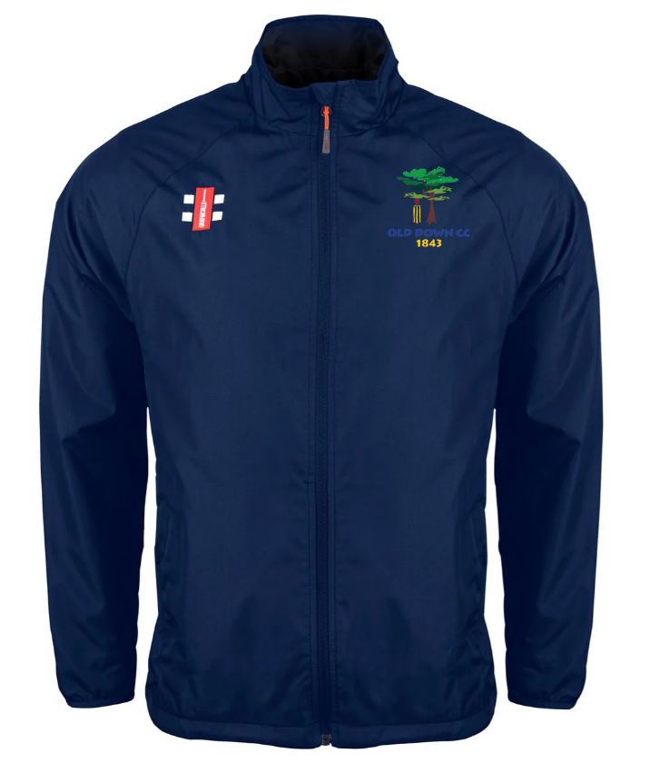 Stay dry in unpredictable weather with the Gray Nicolls Old Down CC Velocity Rain Jacket, featuring a navy blue design, cricket bat logo on the right chest, and green tree with yellow OLD DEAN CC 1847 text on the left.
