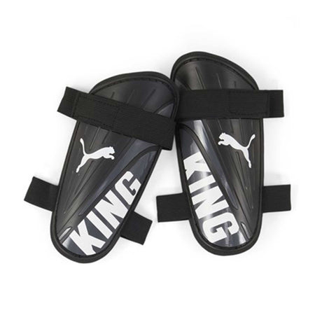 The Puma King Strap Shin Guard by Puma features black guards with white branding and bold KING print, plus black elastic straps for a secure fit and reliable protection during soccer matches.