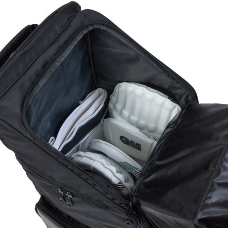 A Gunn & Moore Players Edition Duffle Bag 2026 by Gunn & Moore is unzipped and open, showing white cricket batting pads and gloves neatly arranged in customizable compartments, with space left for a bat, as seen from above.