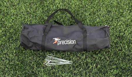 A black Precision Training sports bag rests on green artificial grass with four metal ground stakes—perfect for first touch drills or assembling the Precision Mini Foot Tennis Set for skill training.