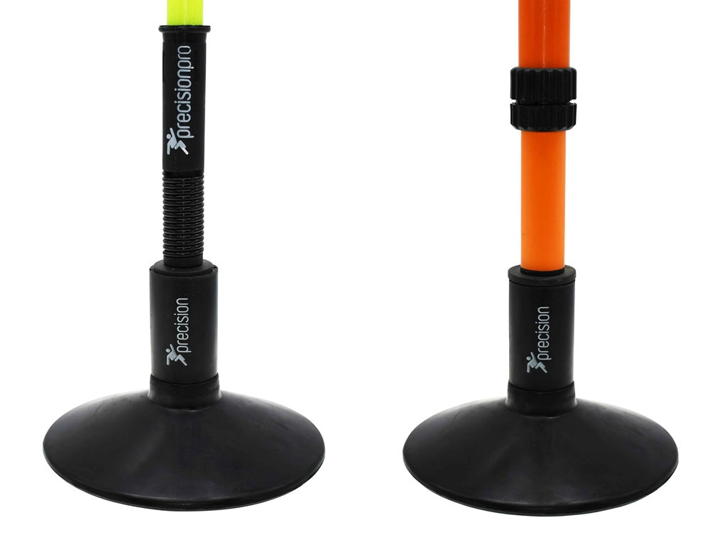 Two adjustable Precision Training poles with weighted rubber bases: the yellow pole has a spring and lock, the orange has a ring adjuster. Both use Precision Rubber Corner & Boundary Pole Bases, branded for Precision Training.