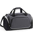 The Quadra Pro Team Holdall by Quadra in Graphite Grey/Black/White features black handles, a shoulder strap, multiple zippered compartments, white trim, a shoe tunnel, and a front pocket—ideal as a 55L gym bag.