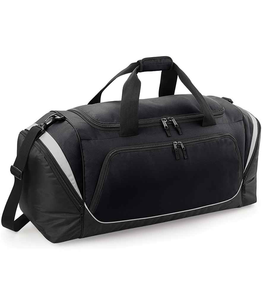The Quadra Pro Team Jumbo Kit Bag by Quadra, in black/light grey polyester, features multiple zippered compartments, two short handles, and a long adjustable shoulder strap. Shown on a white background, it's ideal as a 115L gym or travel bag.