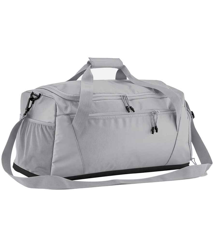 The Quadra Multi-Sport Locker Holdall by Quadra in Ice Grey features recycled polyester, an adjustable shoulder strap, two handles, and multiple zippered compartments, shown against a white background.