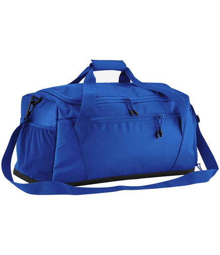 The Quadra Multi-Sport Locker Holdall by Quadra, shown in bright royal, features recycled polyester, a front zippered pocket, racquet pocket, two short handles, adjustable shoulder strap, and side pockets on a white background.