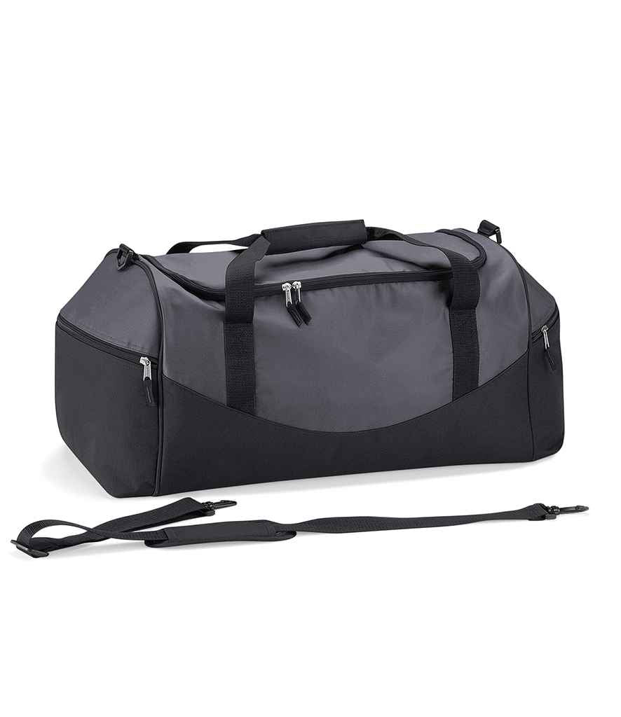 The Quadra Teamwear Holdall by Quadra is a large grey/black/black duffel bag with side pockets, top handles featuring a padded grip, and a detachable shoulder strap shown in front of the bag on a white background.