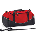 The Quadra Teamwear Holdall by Quadra is a large duffel bag in red, black, and white. It features padded black handles, zippered side pockets, large end pockets, and a detachable adjustable shoulder strap in front of the bag.